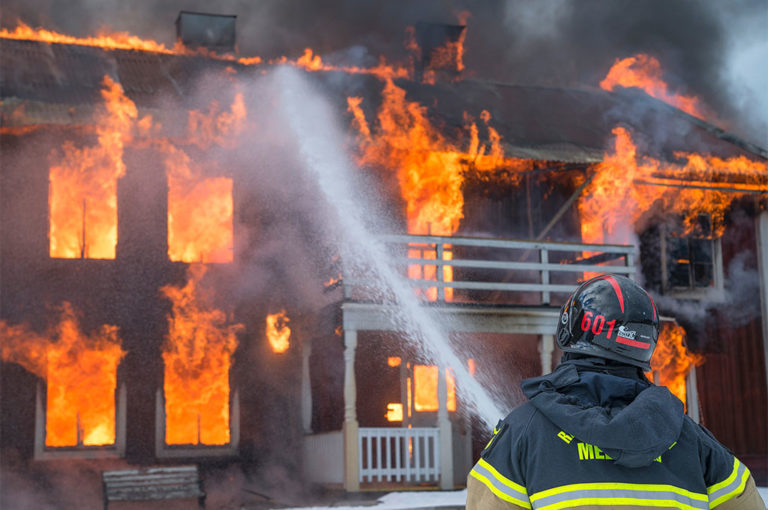 A firefighter sprays a jet of water onto a burning house